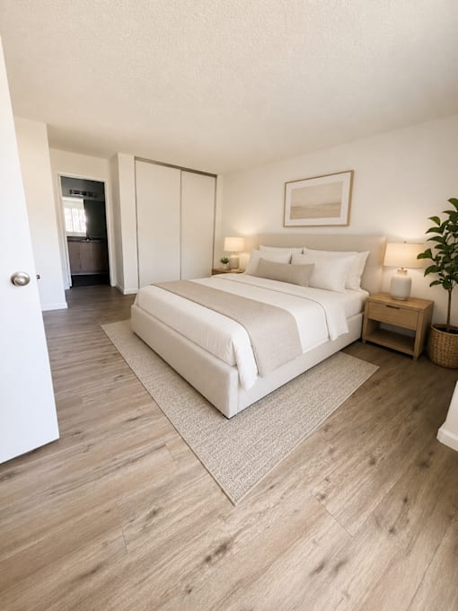 A bedroom with a large bed and a wooden floor.