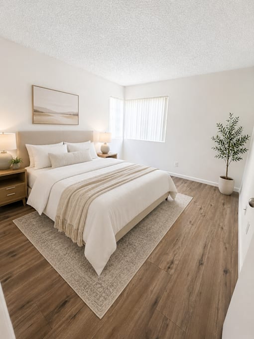 A bedroom with a large bed and a small tree.