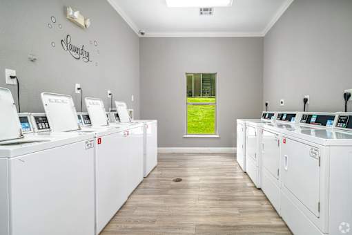 A laundromat with rows of washers and dryers at The Villages at Lost Creek Apartments, San Antonio, Texas