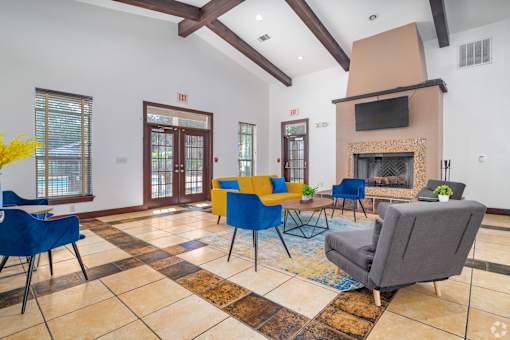 A living room with a fireplace and blue chairs at The Villages at Lost Creek Apartments, San Antonio, Texas