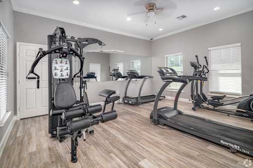 A spacious home gym with a variety of exercise equipment at The Villages at Lost Creek Apartments, San Antonio, Texas