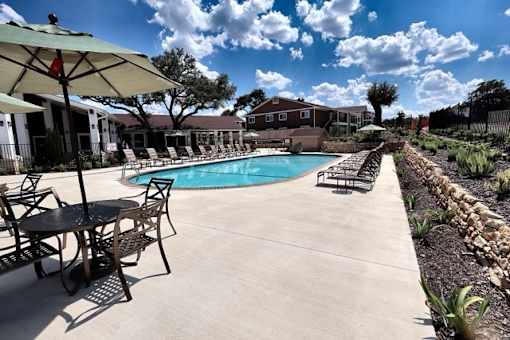 A pool area with chairs and umbrellas.