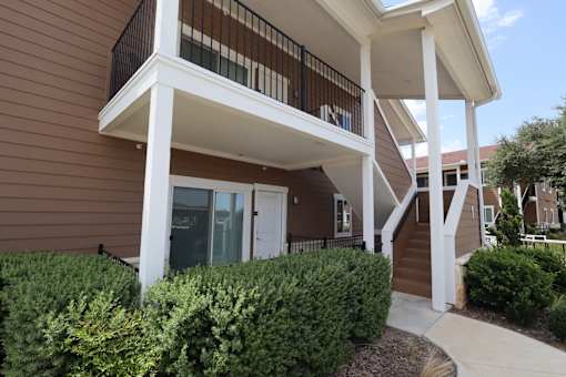 A brown house with a white porch and a glass door.