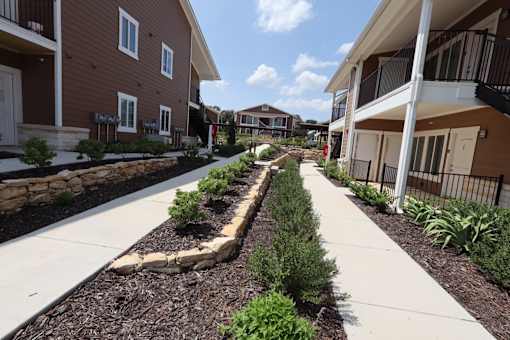 A row of brown houses with a white walkway in between.