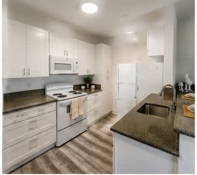 A kitchen with white cabinets and a black countertop.