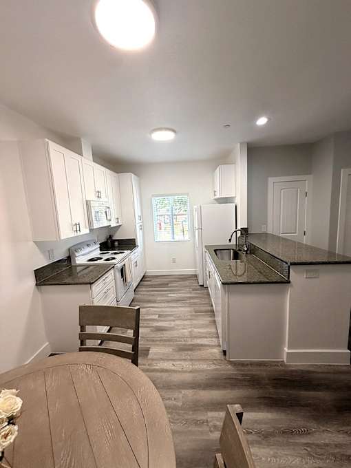 A kitchen with white cabinets and black countertops.