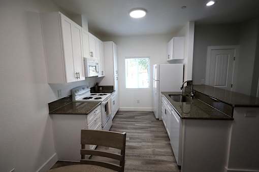 A kitchen with white cabinets and a brown chair.
