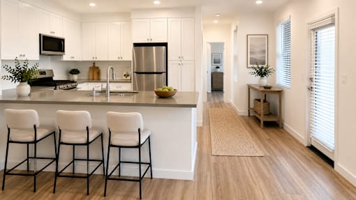 A kitchen with white cabinets and a black fridge.