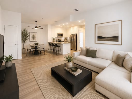 A modern living room with a white couch, a black coffee table, and a dining table with chairs.