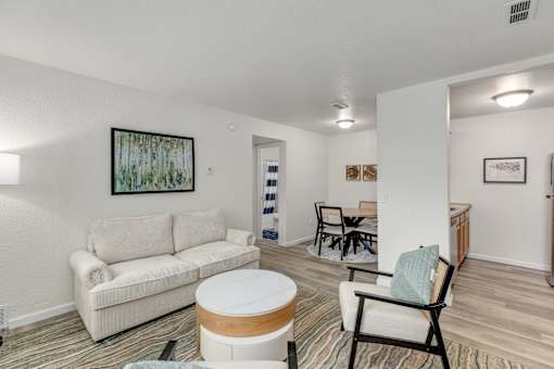 A living room with a white couch and a painting on the wall.