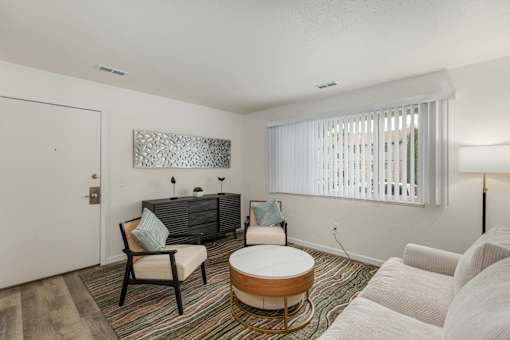 A living room with a white sofa, a wooden coffee table, and a grey couch.