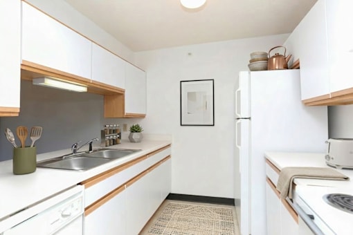 A kitchen with white cabinets and a fridge.