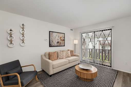 A living room with a couch, chair, and a painting on the wall.