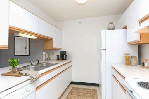 A kitchen with white cabinets and a white fridge.