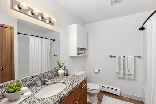 A bathroom with a white toilet, a sink, a mirror, and a towel rack.