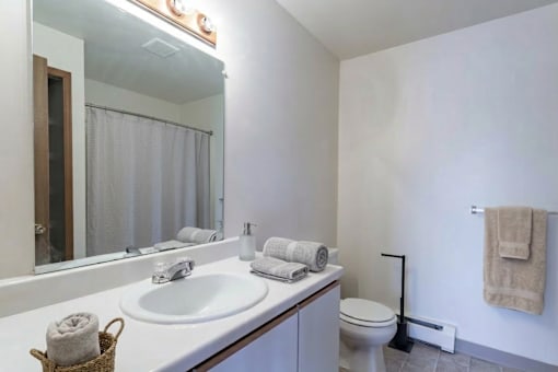 A white bathroom with a toilet, sink, and towel rack.