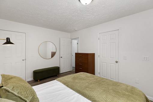 A bedroom with a bed, a bench, and a mirror.