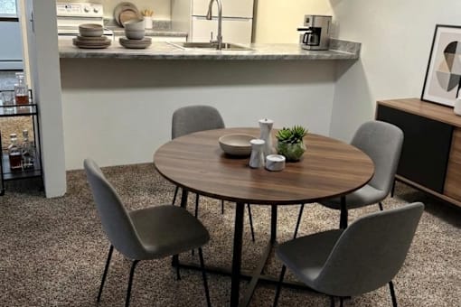 A round table with four grey chairs in a room.