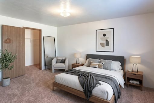 A bedroom with a large bed and a chair.