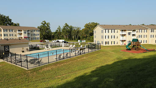 A large grassy area with a pool and a building in the background.