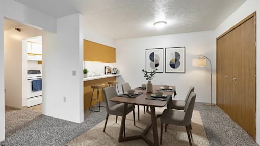 A dining room with a table set for two and a kitchen area in the background.