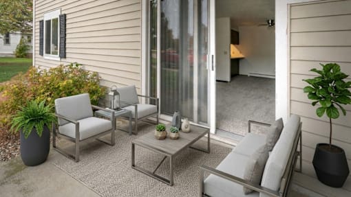 A patio with a table, chairs, and potted plants.