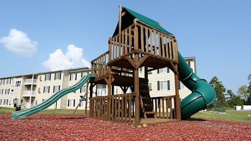 A wooden playground structure with a green slide.