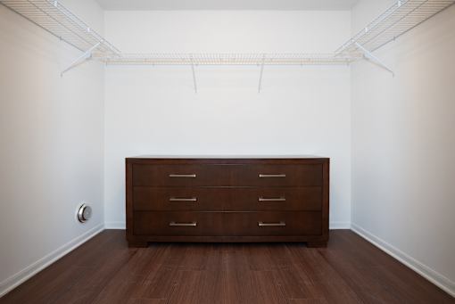 A brown dresser is in a white room with a white ceiling and a white wall.