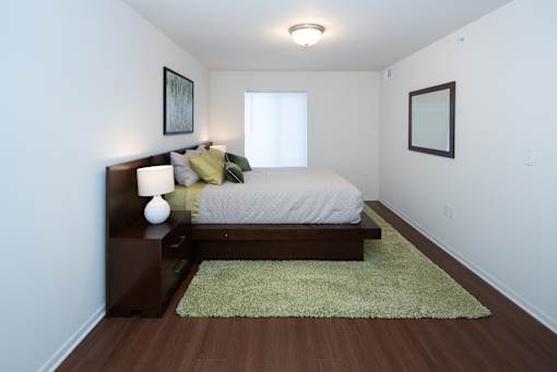 A bedroom with a bed, nightstand, and two pictures on the wall.