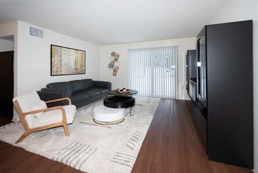 A black couch sits in a living room with a wooden chair and coffee table.