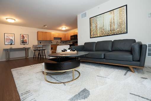 A black leather sofa sits in a living room with a coffee table in front of it.