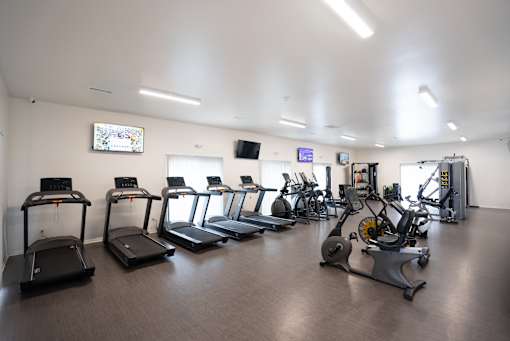 A gym with treadmills, elliptical machines, and other exercise equipment.