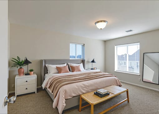 A bedroom with a bed, nightstand, and a plant.