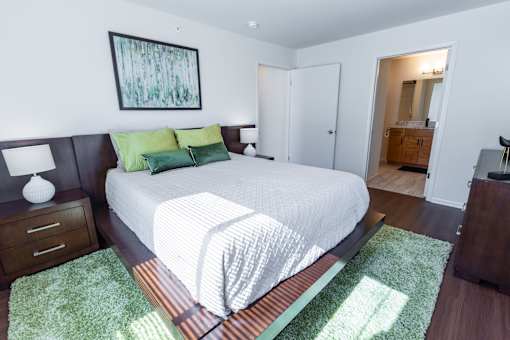 A bedroom with a large bed and a painting on the wall.