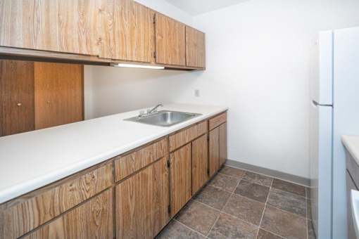 a kitchen with a sink and cabinets and a refrigerator