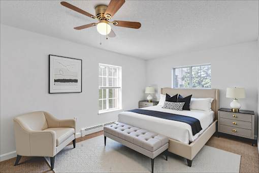 A bedroom with a bed, chair, and a ceiling fan.