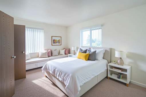 A bedroom with a bed, a couch, and a lamp.