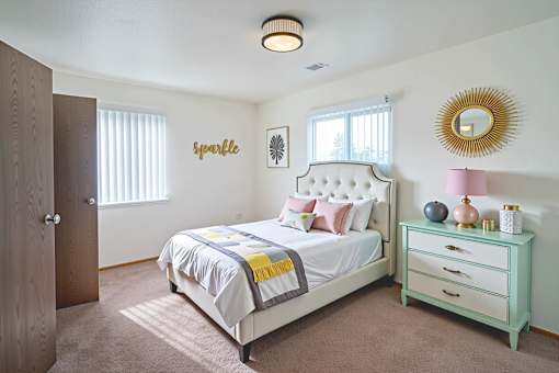 A bedroom with a bed, nightstand, and a mirror on the wall.