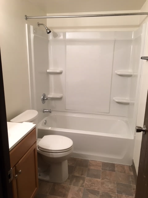 a white bathroom with a toilet and a tub