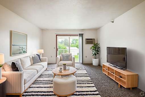 A living room with a white couch, a coffee table, and a television.