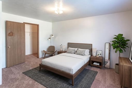 A bedroom with a bed, nightstand, and chair.