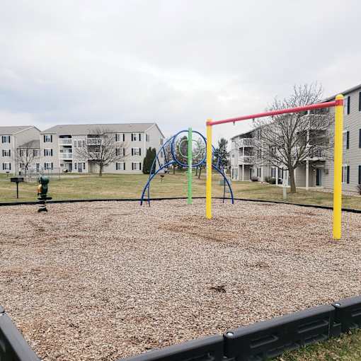 A playground with a red swing set and a blue slide.