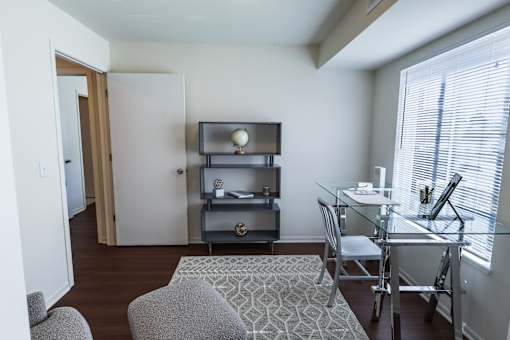 A living room with a grey couch, a glass table, and a television on a stand.