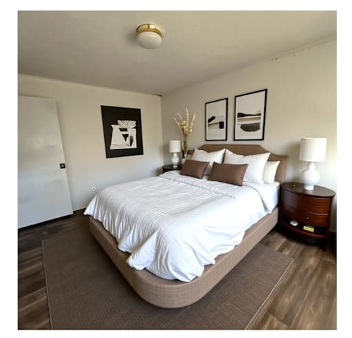 A bedroom with a large bed and two framed pictures on the wall.