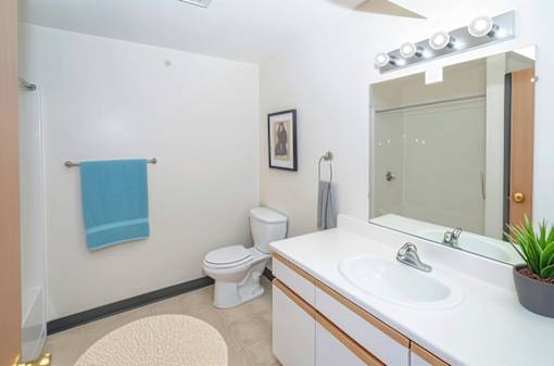 A bathroom with a white sink, toilet, and a blue towel hanging on the wall.
