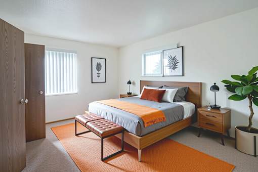A bedroom with a bed, nightstand, and a plant.