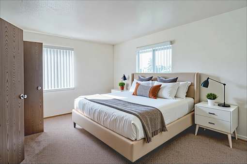 A bedroom with a bed, nightstand, and window.