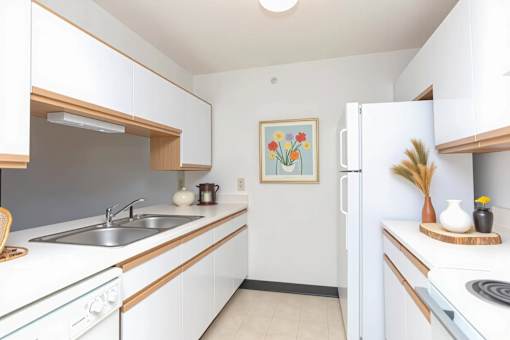 A kitchen with white cabinets and a painting on the wall.