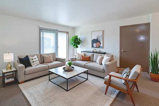 A living room with a grey couch, a coffee table, and a wooden chair.