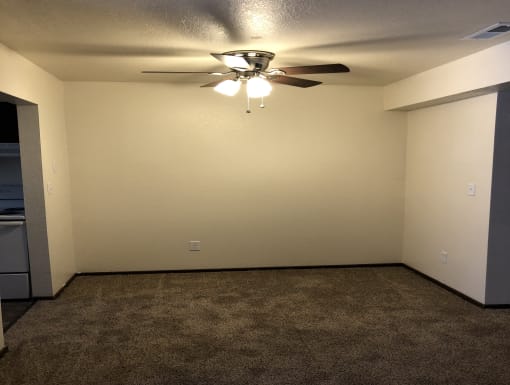 a room with a ceiling fan and a carpet